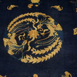 Close-up of a dark indigo rug with a central gold medallion featuring mythical creatures and foliage.