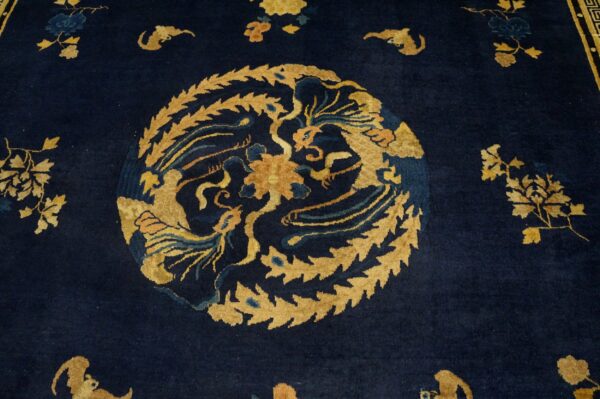 Close-up of a dark indigo rug with a central gold medallion featuring mythical creatures and foliage.