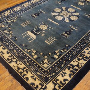 Dark blue rug with beige medallion and border patterns lying on warm wood planks.