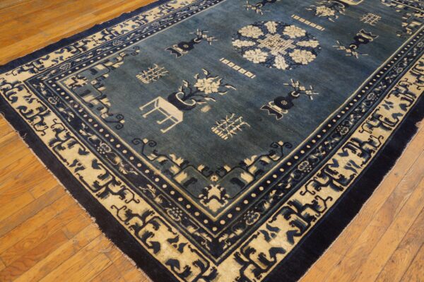 Dark blue rug with beige medallion and border patterns lying on warm wood planks.