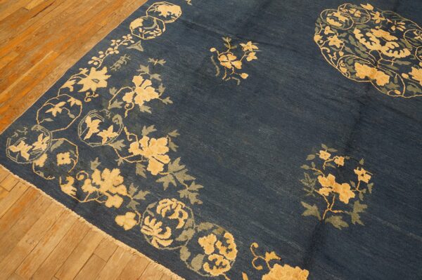 Deep blue rug with an ornate beige and sage green floral pattern on light brown hardwood planks.
