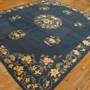 Navy area rug featuring high-contrast gold and sage floral patterns on rustic wood flooring.