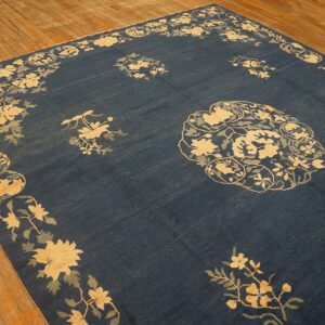 Dark blue rug with pale yellow and sage floral motifs displayed on light brown wood flooring.
