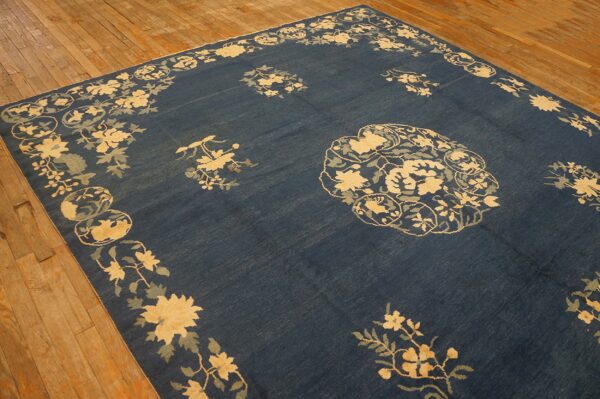 Dark blue rug with pale yellow and sage floral motifs displayed on light brown wood flooring.