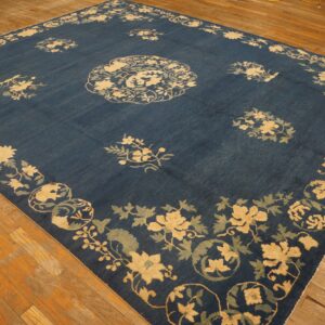 Square blue rug featuring large yellow and pale blue floral motifs on exposed wood planks.
