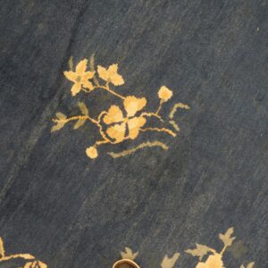 Dark navy rug with a visible low pile texture featuring stylized floral motifs in gold and pale green.
