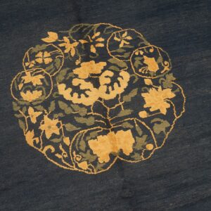 Navy blue rug detail showing a round medallion with stylized yellow and olive green floral designs.