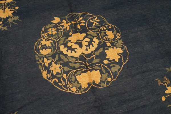 Navy blue rug detail showing a round medallion with stylized yellow and olive green floral designs.