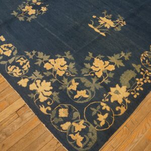 Indigo blue rug featuring yellow and sage floral motifs displayed on warm wooden plank flooring.