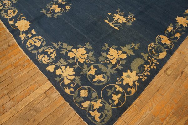 Indigo blue rug featuring yellow and sage floral motifs displayed on warm wooden plank flooring.