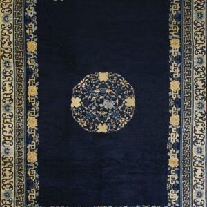 Dark blue rug with a circular floral medallion and wide multi-banded border in tan, gold, and blue.