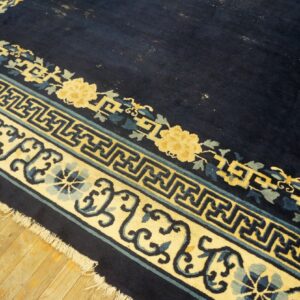 High pile navy rug with yellow, blue, and teal geometric and floral borders visible on wood floor.