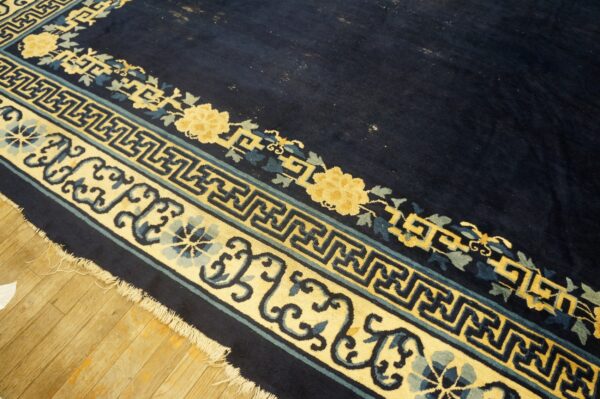 High pile navy rug with yellow, blue, and teal geometric and floral borders visible on wood floor.