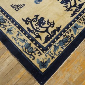 Cream rug with detailed navy and dusty blue floral and butterfly borders on distressed wood planks.