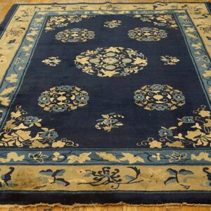 A deep navy rug with beige and light blue circular floral medallions lies on polished hardwood floorboards.