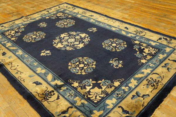 Navy blue and gold rug featuring ornate floral medallions and borders laid on wood flooring.