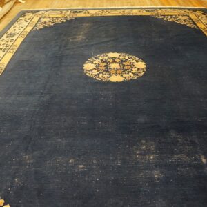 Ornate dark blue rug with contrasting gold and cream floral patterns on hardwood flooring.