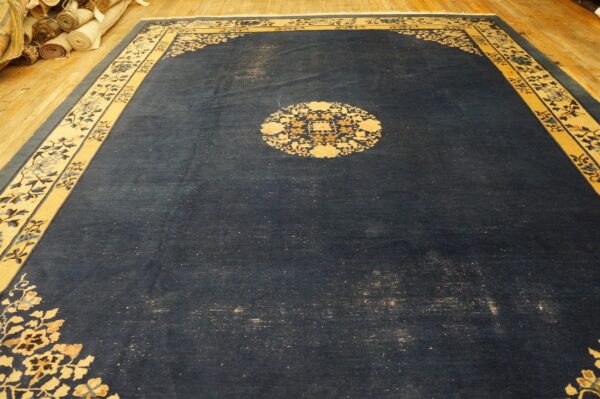 Ornate dark blue rug with contrasting gold and cream floral patterns on hardwood flooring.