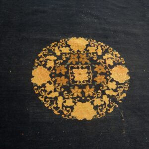 A dark blue rug displays a detailed circular pattern of gold and rust-colored flowers.