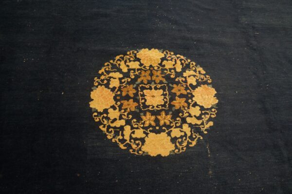 A dark blue rug displays a detailed circular pattern of gold and rust-colored flowers.