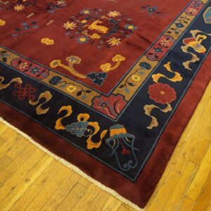 Red field rug featuring floral and deer patterns, framed by navy and gold borders on hardwood flooring.