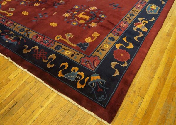 Red field rug featuring floral and deer patterns, framed by navy and gold borders on hardwood flooring.