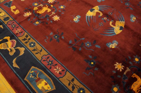 Deep red rug with gold and blue animal and floral patterns, featuring a contrasting dark navy and brown border.