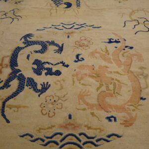 Beige rug featuring a detailed central pattern of facing navy blue and peach stylized dragons and clouds.