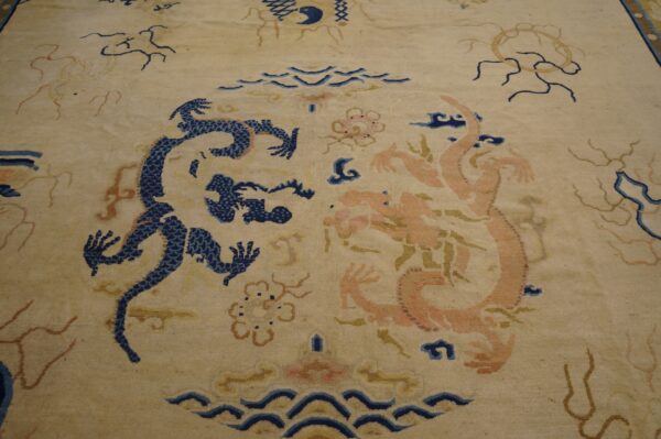 Beige rug featuring a detailed central pattern of facing navy blue and peach stylized dragons and clouds.