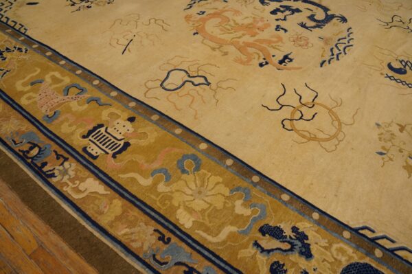 Pale yellow rug with peach and navy dragon patterns features a wide golden border on wood flooring.