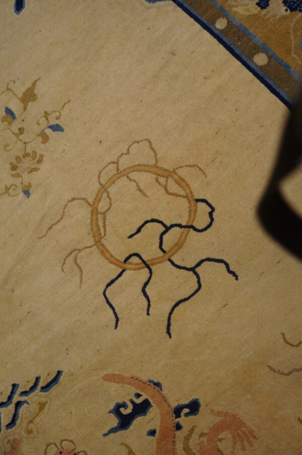 Beige rug detail featuring stylized floral and circular motifs in navy, gold, and orange accents.