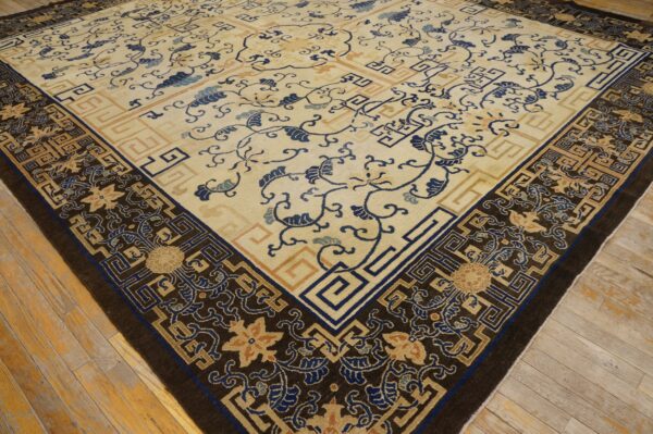 Detailed cream rug with blue floral scrolls and intricate dark brown geometric borders on wood flooring.