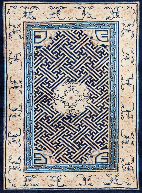 A high-contrast rug with a navy geometric key pattern field bordered by light blue and cream floral motifs.