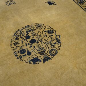 Tan low-pile rug featuring a large dark blue circular medallion and an intricate floral border pattern.