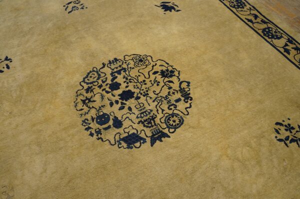 Tan low-pile rug featuring a large dark blue circular medallion and an intricate floral border pattern.