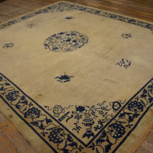 Large square beige rug with deep indigo blue floral and medallion patterns on wood planks.