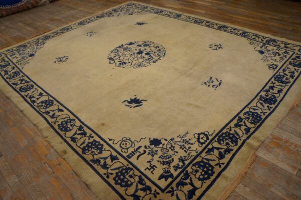 Large square beige rug with deep indigo blue floral and medallion patterns on wood planks.