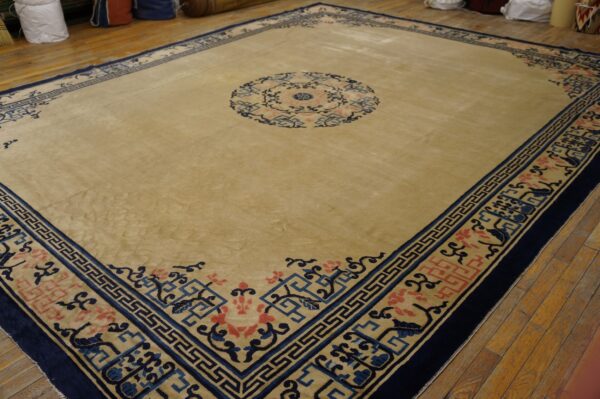 Beige rug with a central circle and wide borders detailed in navy blue and coral pink on wood flooring.