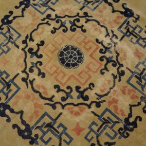 Gold tone rug detail showing a circular central medallion in navy, light blue, and pink geometric motifs.