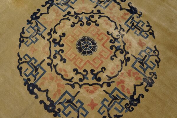 Gold tone rug detail showing a circular central medallion in navy, light blue, and pink geometric motifs.