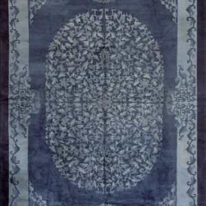 Monochromatic deep blue rug with a detailed oval center and lighter blue foliate scrollwork borders.