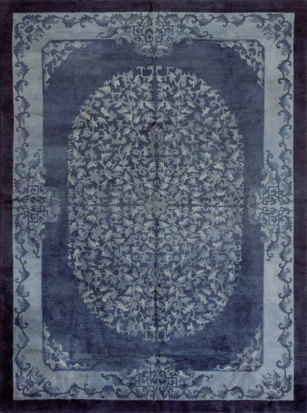 Monochromatic deep blue rug with a detailed oval center and lighter blue foliate scrollwork borders.