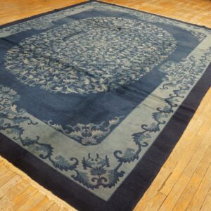 Ornate navy and pale blue rug with a central medallion and wide borders on light wooden flooring.