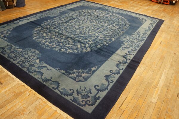 Ornate navy and pale blue rug with a central medallion and wide borders on light wooden flooring.