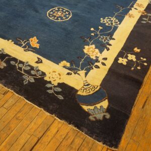 Navy and cream floral rug featuring a vase pattern borders old amber-toned wooden flooring.