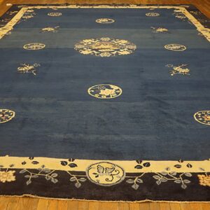 Deep blue rug with contrasting beige medallion and wide floral borders on light wood floor.