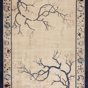 A beige rug with a navy blue border features a blossoming tree branch pattern in the center.