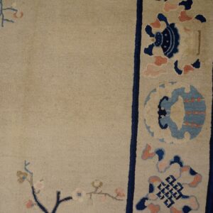 Beige high-pile rug detail showing floral and geometric patterns, blue border, and adjacent wood floor.