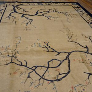 Beige rug featuring sprawling navy branches and pink flowers, framed by a patterned navy and light blue border.