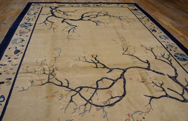 Beige rug featuring sprawling navy branches and pink flowers, framed by a patterned navy and light blue border.